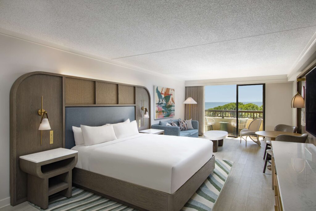 Bright bedroom with balcony and ocean view.