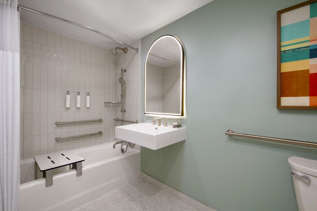 Modern bathroom with accessibility features and mirror.