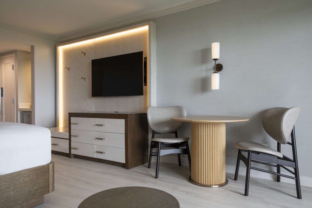 Hotel room seating area with TV and desk.