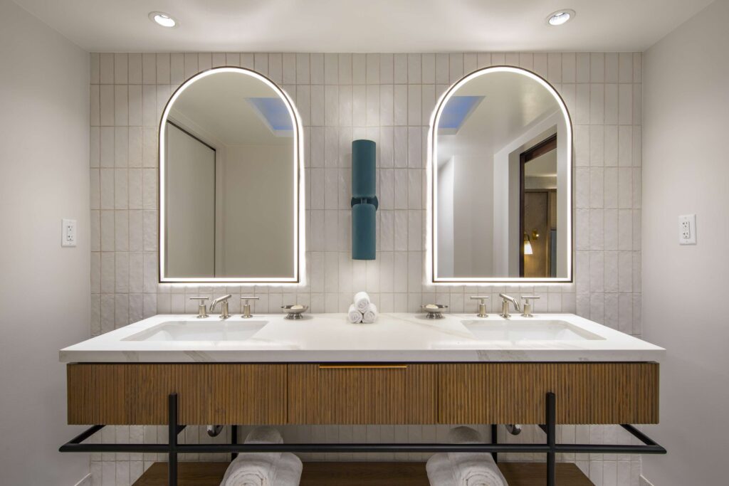 Elegant double vanity with illuminated arched mirrors.