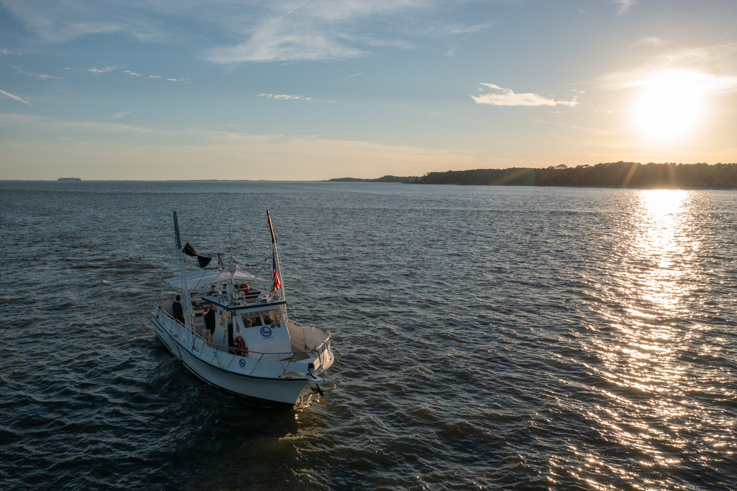 Boat sailing on ocean at sunset.