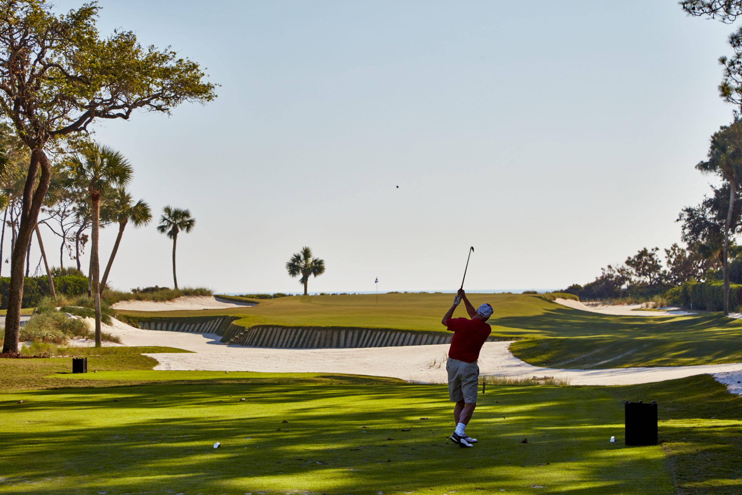 Golfer taking a swing on a lush course.