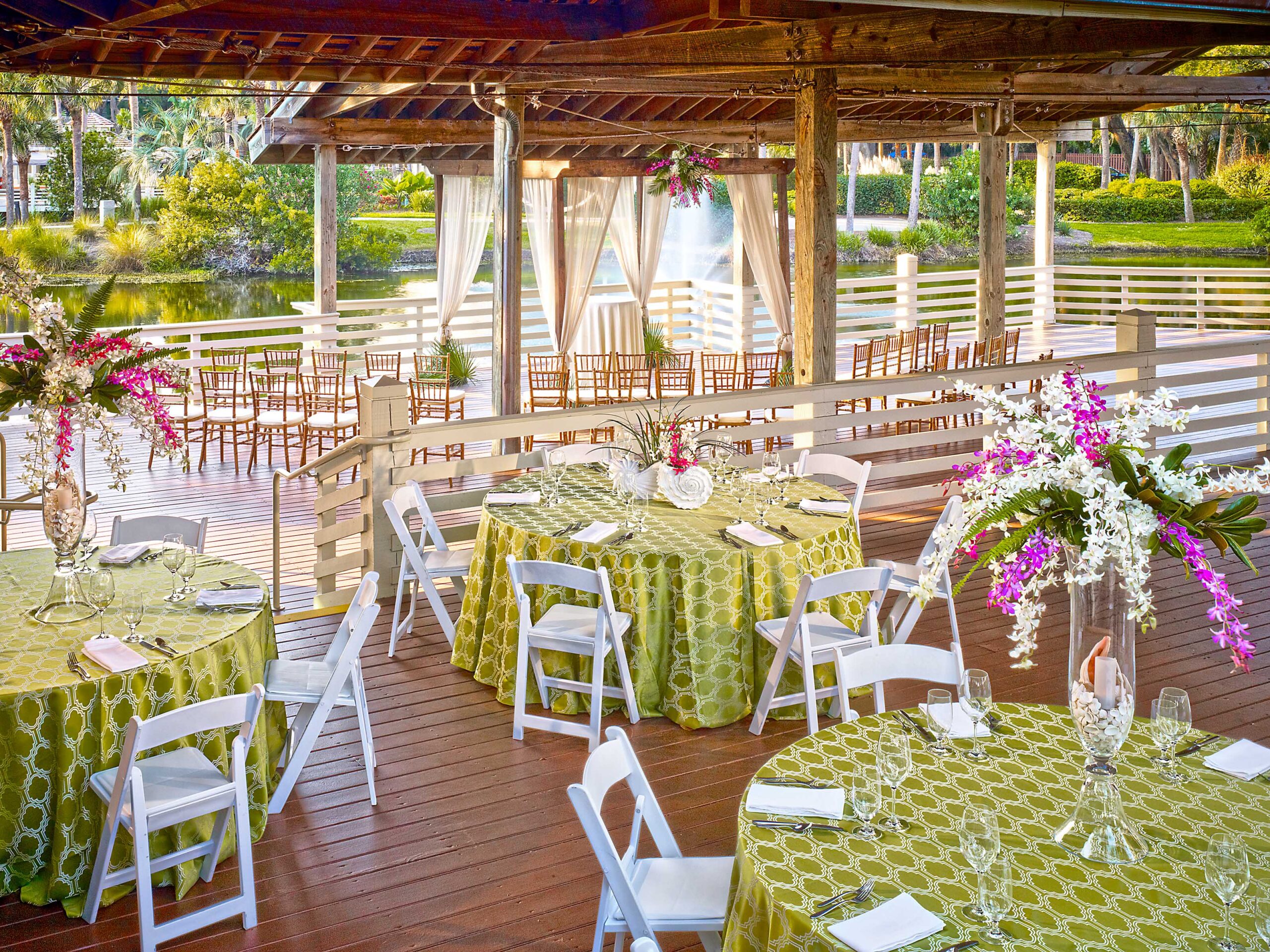 Outdoor venue with tables and decorative floral arrangements.