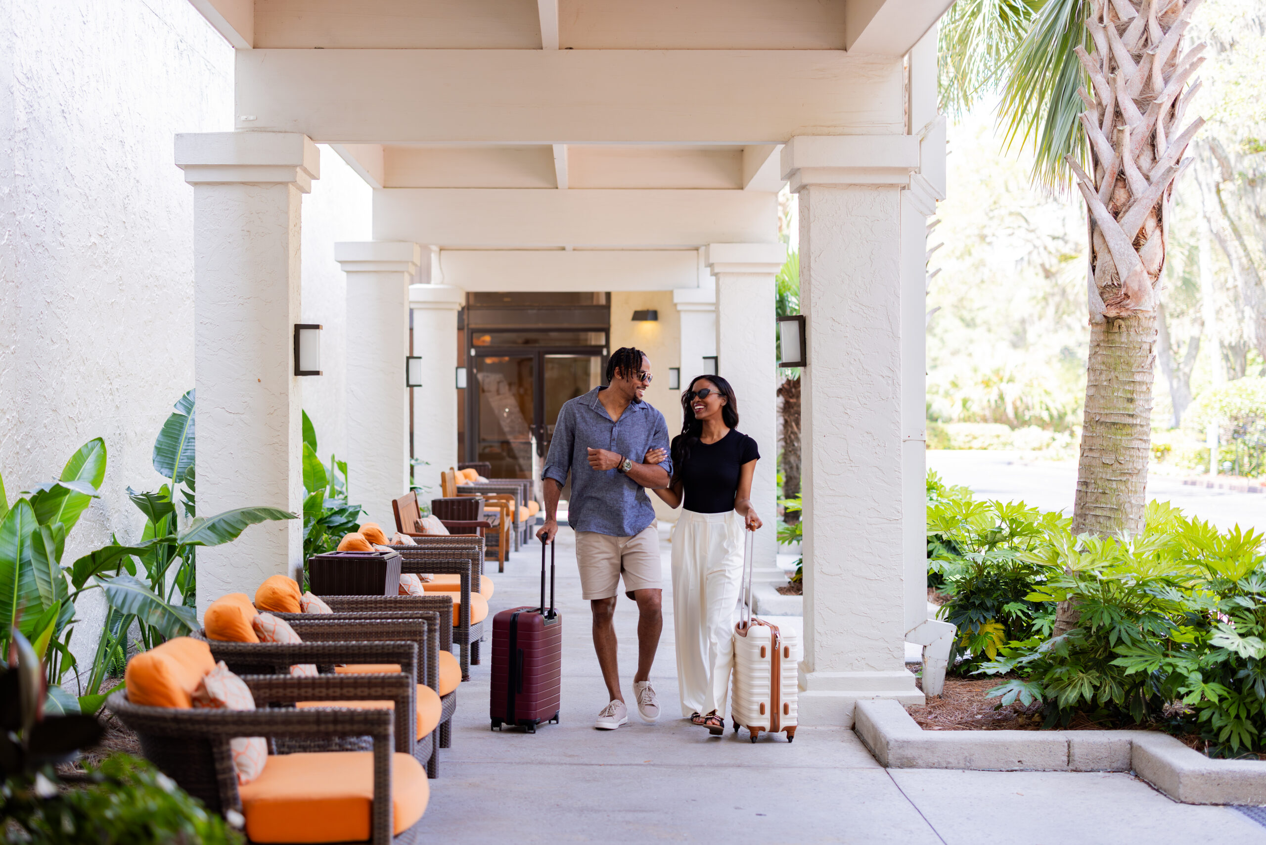 Hilton Head Island image of a couple walking down the resort with their suitcases.