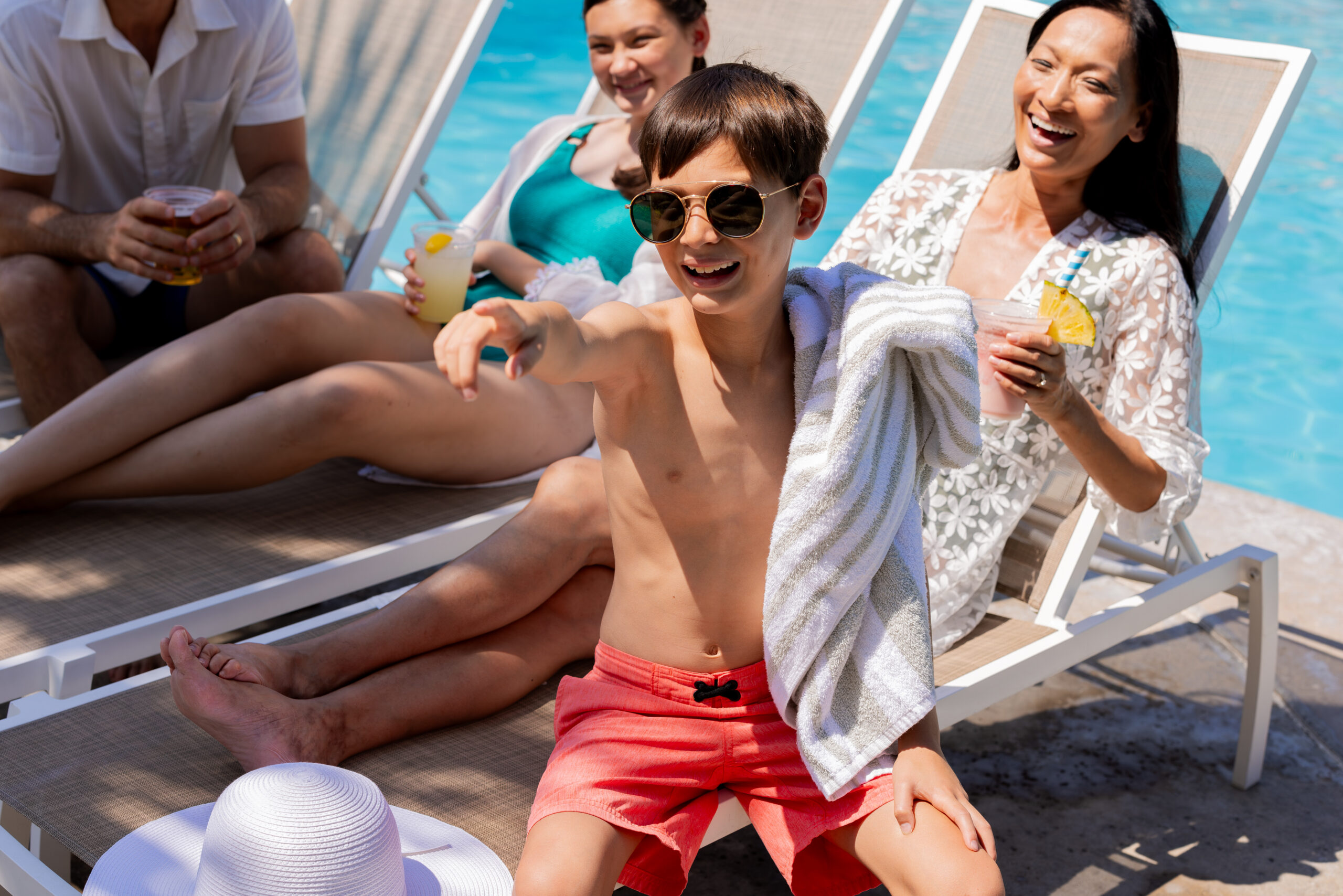 Family relaxing poolside with refreshing beverages.