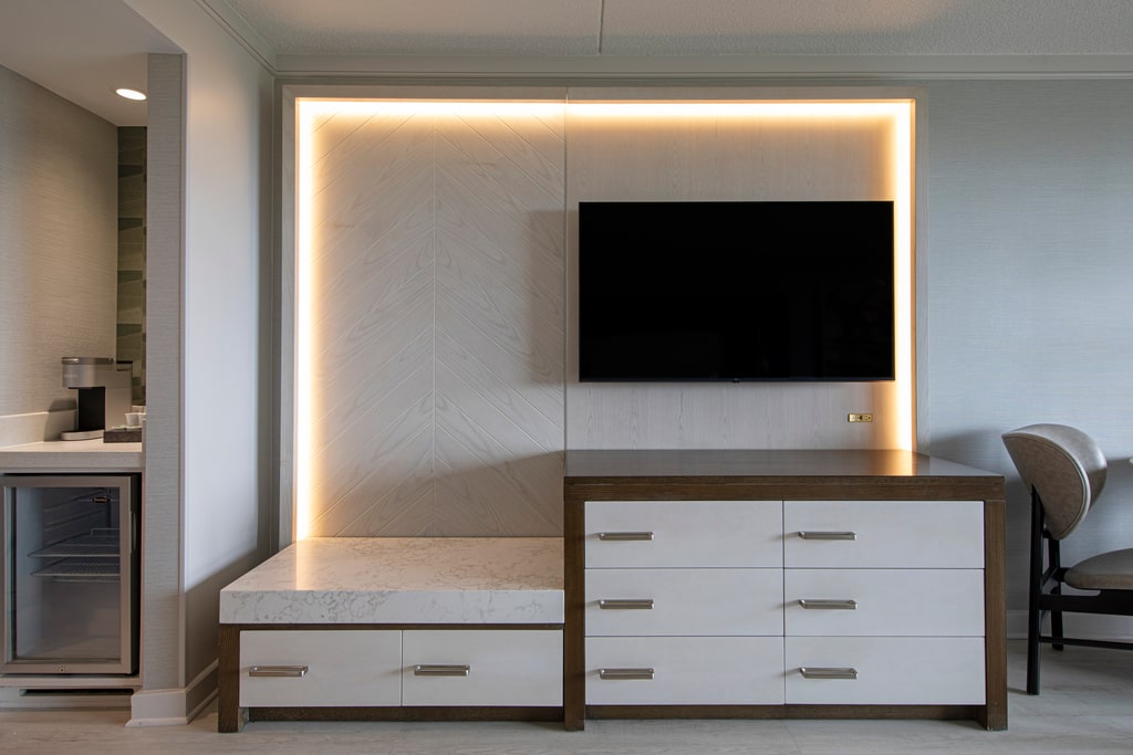 Hotel room dresser with mounted flat-screen TV.