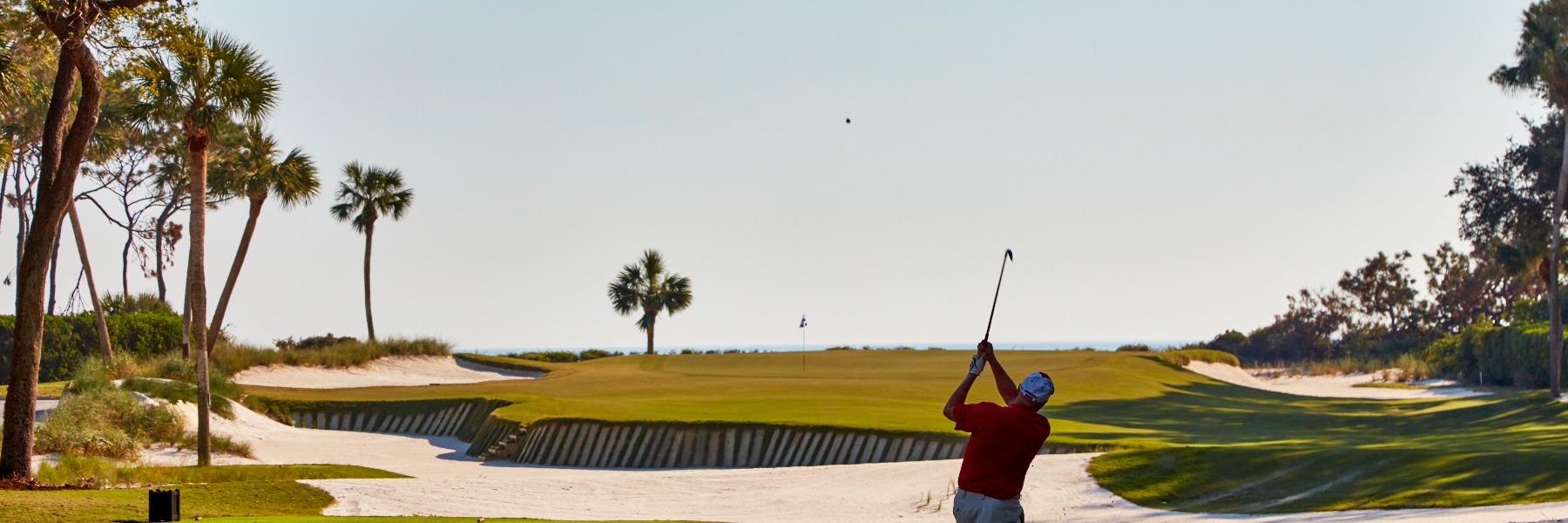 Golfer taking a swing on a lush course.