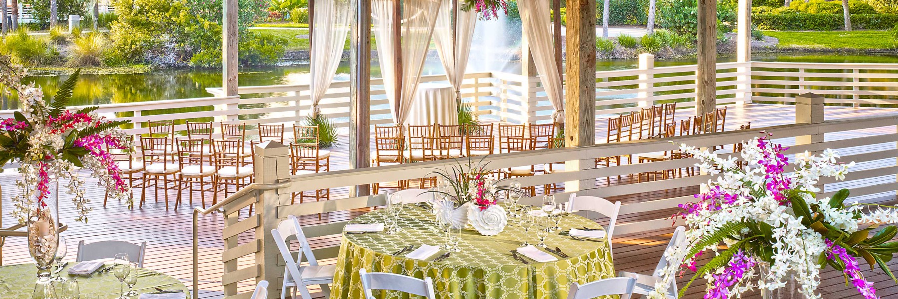 Outdoor venue with tables and decorative floral arrangements.